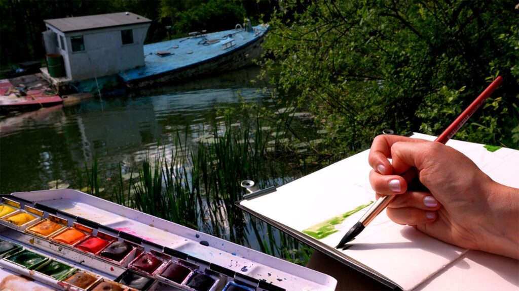 a plein air artist is painting a sunken boat on the canal